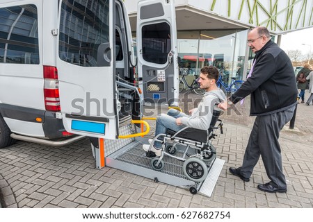 Side view of taxi driver assisting man on wheelchair to board van outside building Royalty-Free Stock Photo #627682754