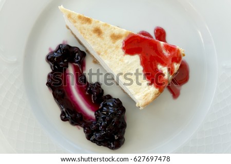 Overhead close up of a slice of cheesecake with blueberry jam on a plate
