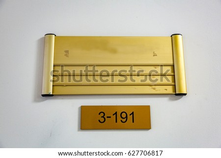 Yellow nameplate with black figures 3-191 hanging on a light wall
