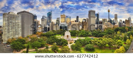 Sydney hyde park and CBD cityline on a bright autumn day. Colourful trees around ANZAC memorial and tall towers of the city. Royalty-Free Stock Photo #627742412
