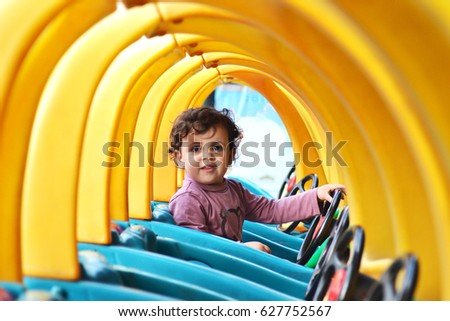 happy girl sited in a colorful toy car, looking to the camera Royalty-Free Stock Photo #627752567