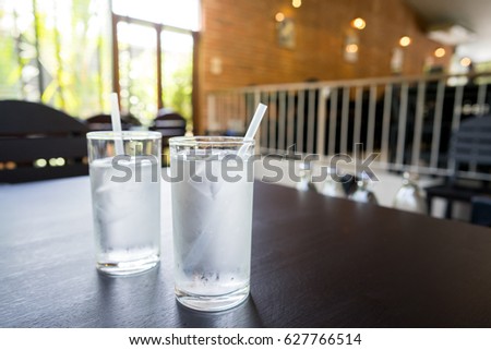 selective focus of cold water in a glass on wooden table in restaurant