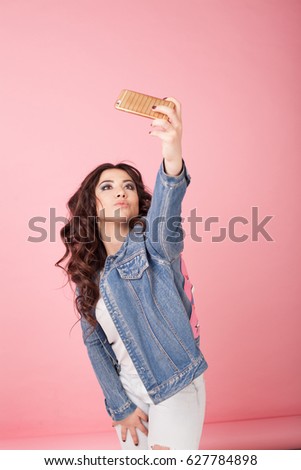 girl in denim jacket make photo on phone pink