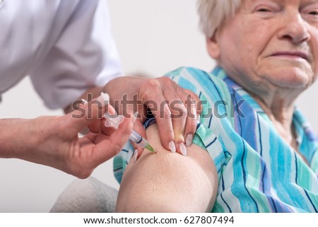 Nurse giving a vaccine to an old woman