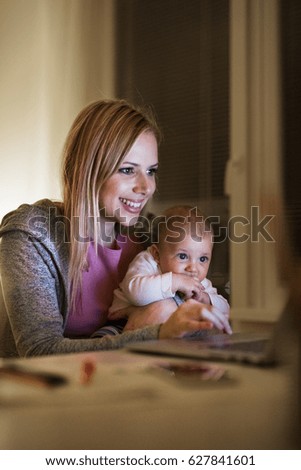 Mother with son in the arms, working on laptop