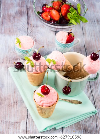Home made strawberry and cherry ice cream served in waffle cups and cones on a ceramic tray. Vintage mood
