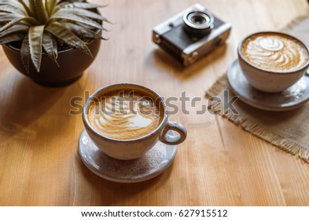 Coffee on a wooden table, flower and camera