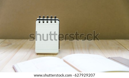 Small note book paper (notepad) stand for writing information with pencil and book on wood table. Blank or free space for text