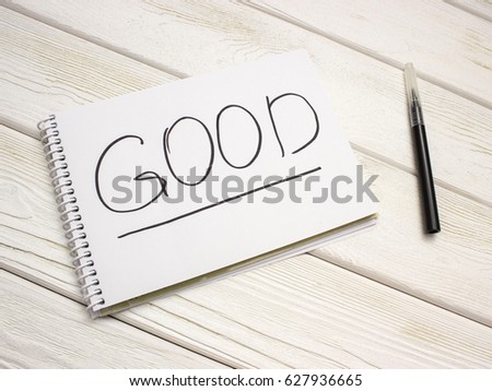 A notebook with an inscription is good and black marker on white wooden table