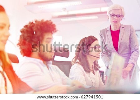 Mature businesswoman with operators working in office