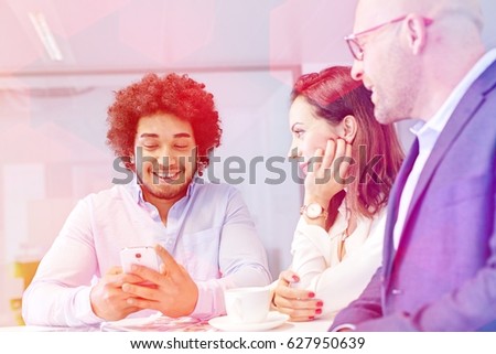 Smiling young businessman using mobile phone with colleagues in office