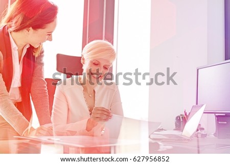 Smiling businesswoman and female manager with project in office