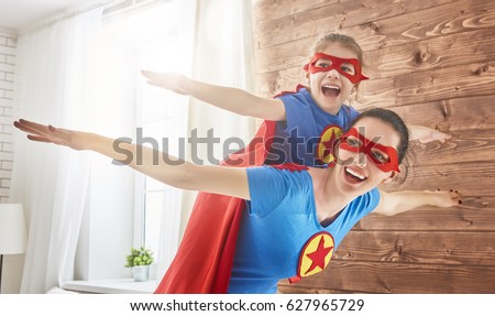 Mother and her child playing together. Girl and mom in Superhero costume. Mum and kid having fun, smiling and hugging. Family holiday and togetherness.