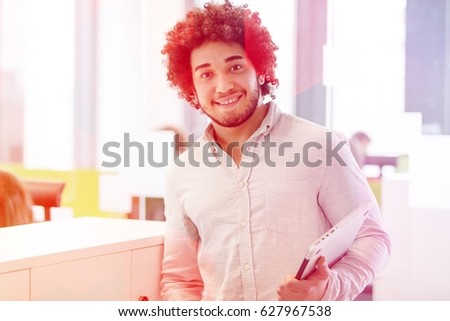 Portrait of smiling young businessman holding laptop in office