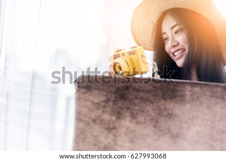 beautiful Asian Woman hold retro yellow camera with happiness and joyful near window white room background