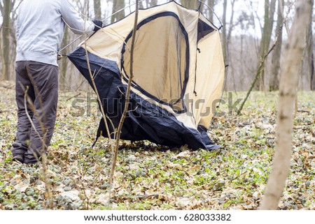 Young man putting a tent in the woods