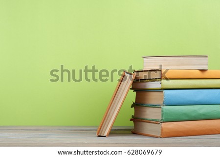 Stack of books on wooden table on green wall background. Copy space for text.Back to school. Education concept.