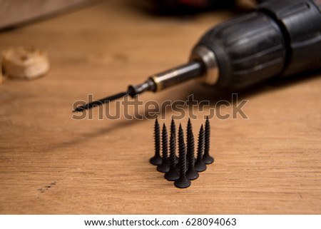 Bulk of screws on wood board and cordless screwdriver