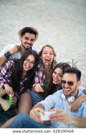 Happy young group of people taking selfies on beach in summer