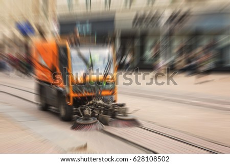 Abstract blurred image of a sweeper vehicle sweeping the street of the city on the tram railway, defocused with radial blur in post production