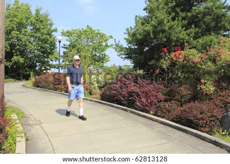 Summer scene of man walking down a sloped sidewalk near Beaverton, Oregon Sunset Transit Center.