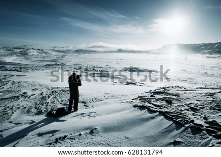 Man photographer with camera at winter mountain