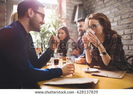Happy colleagues from work socializing in restaurant and eating together Royalty-Free Stock Photo #628137839