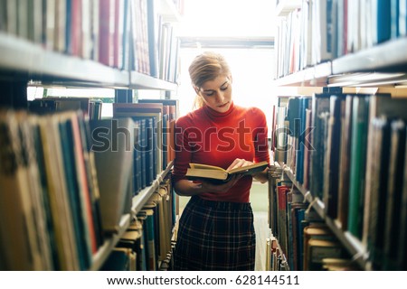 Woman reading a book in library. Portrait of college girl reading book in library