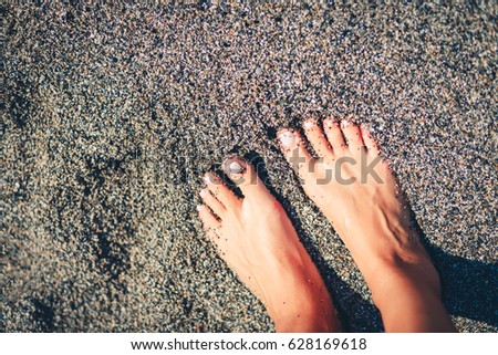 Female feet stand on beach with vintage tone. Stylish toned picture. Filtered shot. Vintage toned image. Stylish toned picture.