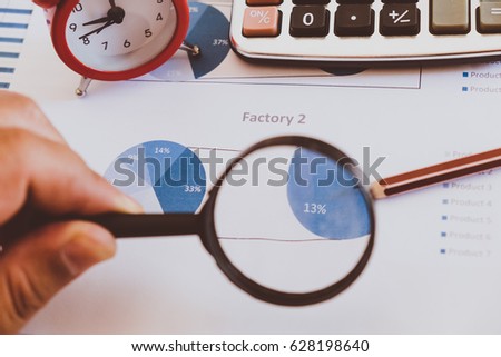Business analytics and statistics. Businessman study report using a magnifying glass.

