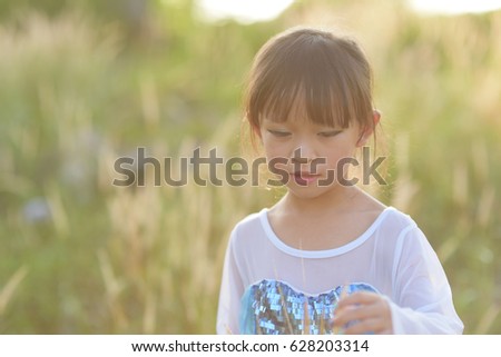 Little asian girl wearing a princess dress in action in grass fields.