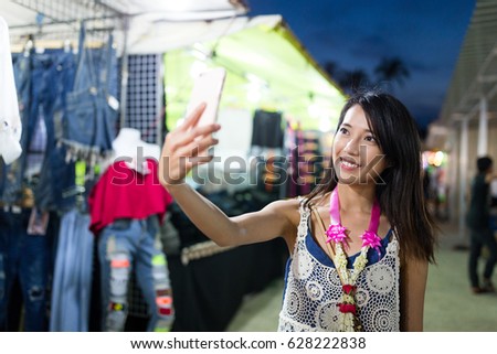 Woman taking selfie by mobile phone in street market