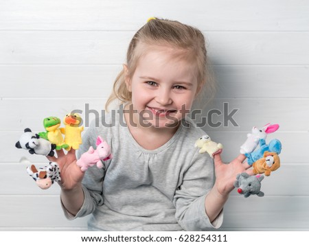 Lovely small girl with doll puppets on her hands, smiling and playing