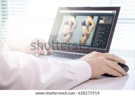 Professional photo editor retouching an image of a woman. Transforming girl skinnier and slim with editing software. Focus on mouse hand. Beauty standards, body image and post production concept.