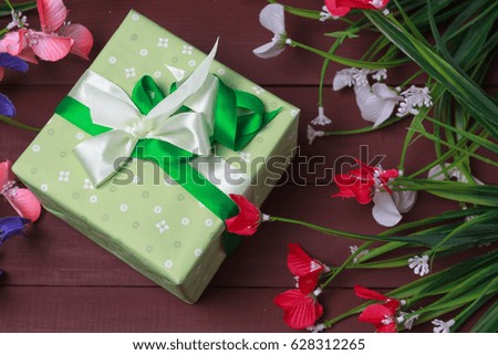 Border of flowers with Mother's Day gift box and tag against a rustic wood background