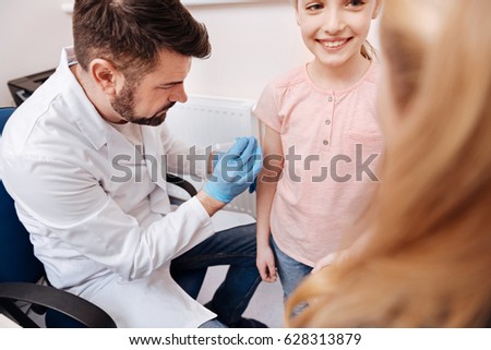 Competent doctor vaccinating little girl against season diseases