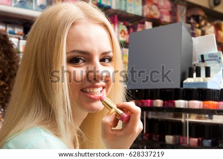 Beautiful  blondie selecting lipstick in store Royalty-Free Stock Photo #628337219