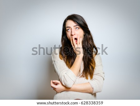 Beautiful woman yawns, bored, isolated on gray background