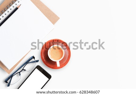 Modern white office desk table with laptop computer, smartphone with black screen over a notebook and cup of coffee. Top view with copy space, flat lay. Office desk table concept.