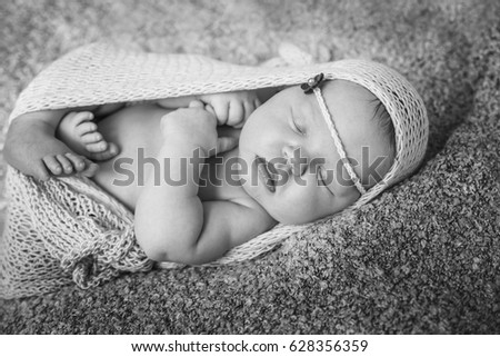 Sleeping newborn baby girl. Baby girl lies wrapped in a  knit fabric.
