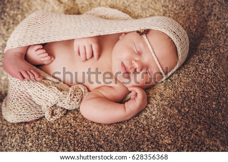 Sleeping newborn baby girl. Baby girl lies wrapped in a beige knit fabric.