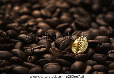 Individuality, standing out  from a crowd concept, close up of a single bright, gold coffee bean over many dark ones with copy space