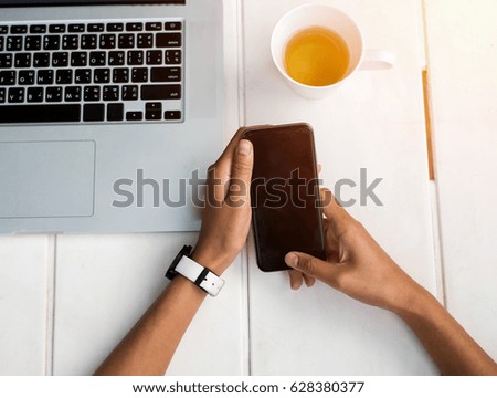 Businessman holding a smart phone on wood table at office