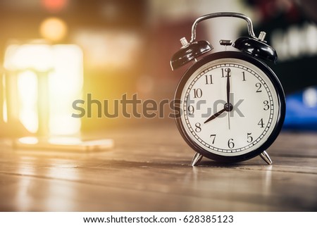 8 o'clock time retro clock on wood table with sun light background