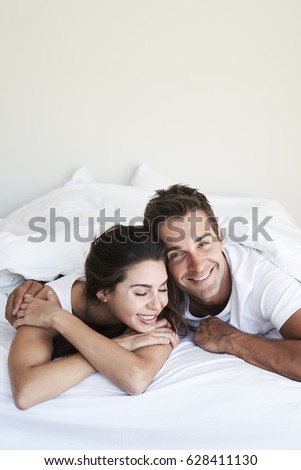 Good looking couple relaxing in bed, smiling