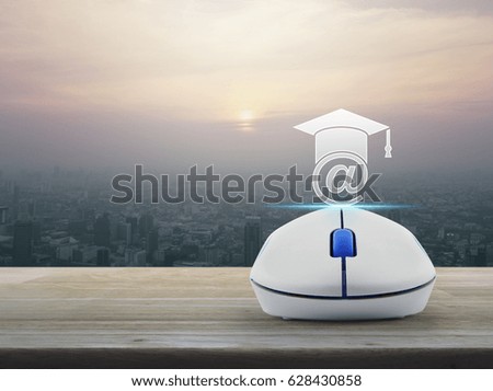 Wireless computer mouse with e-learning icon on wooden table over modern city tower at sunset, vintage style, Study online concept