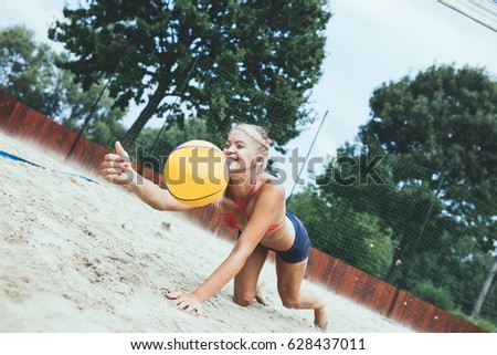 Young beautiful woman playing beach volleyball on sunny day.