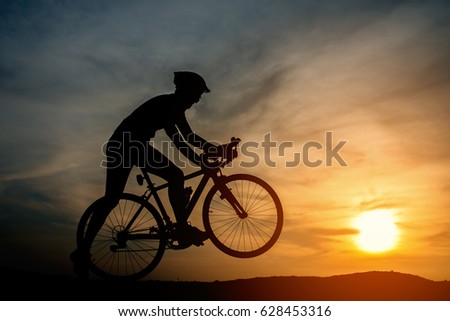 Silhouette of young man riding a bicycle on the sunset