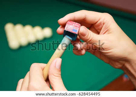Billiard player rubs chalk his cue. Details of the game of billiards.