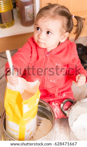 Little disaster in the kitchen.Waggish girl playing at kitchen with vessel and meal